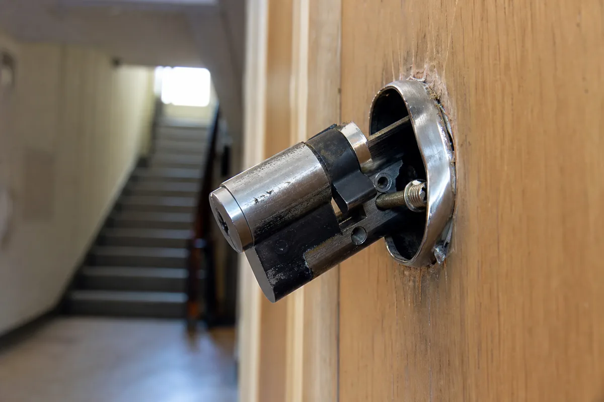 Porte palière d’un immeuble lyonnais avec un cylindre de serrure arraché après une effraction